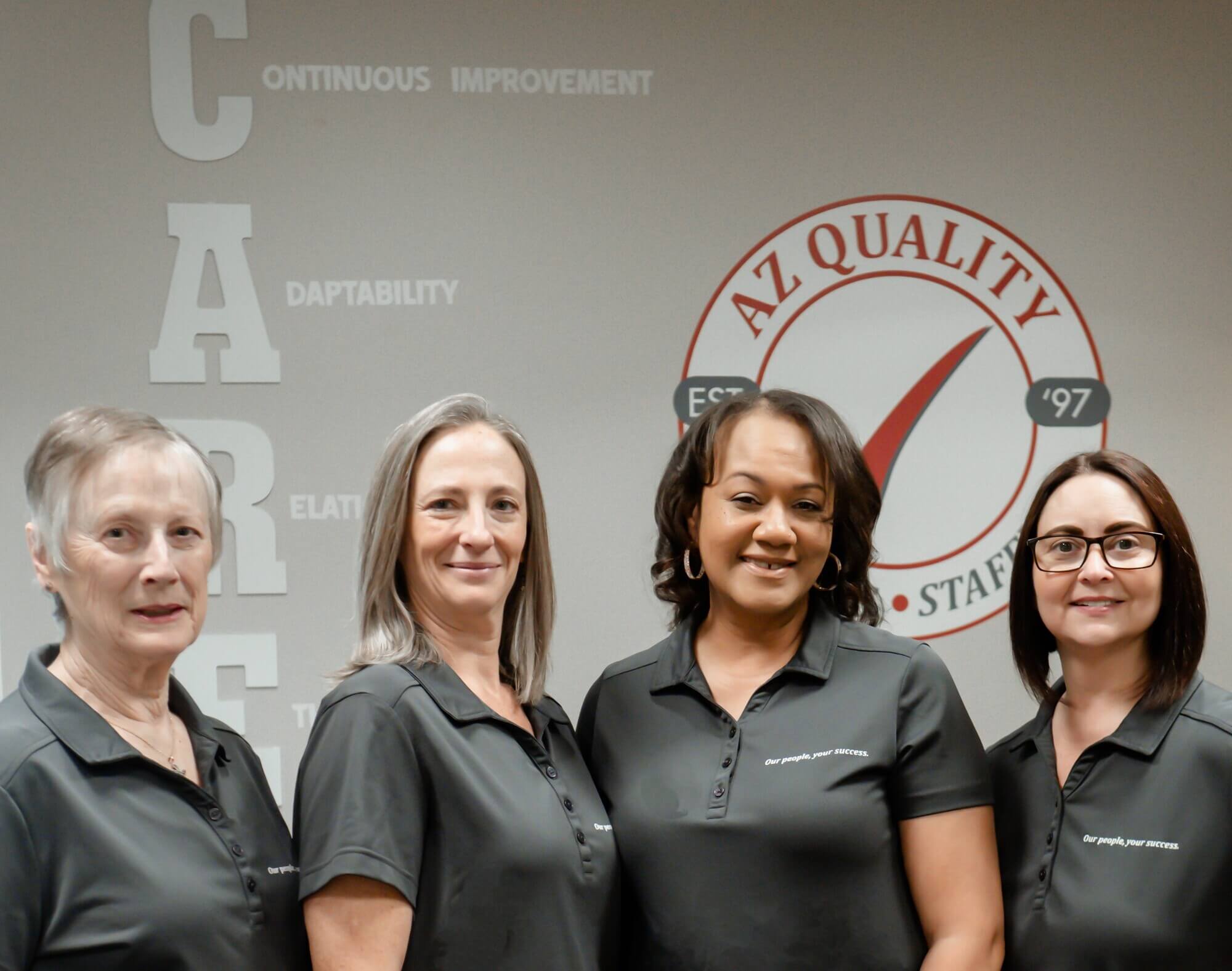 A Z Quality team members standing together in front of A Z Quality branded wall